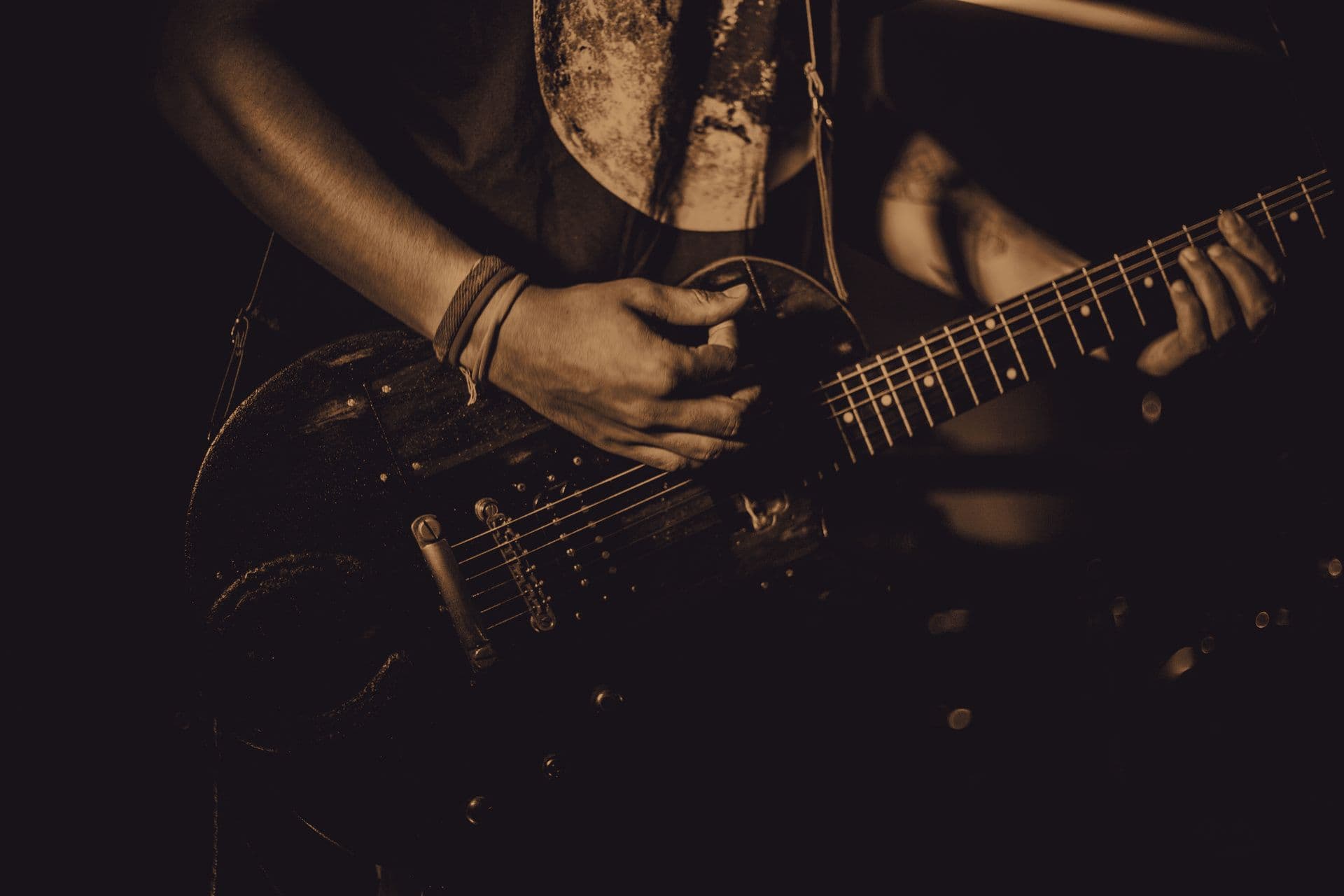 A guitarist playing on a dark stage