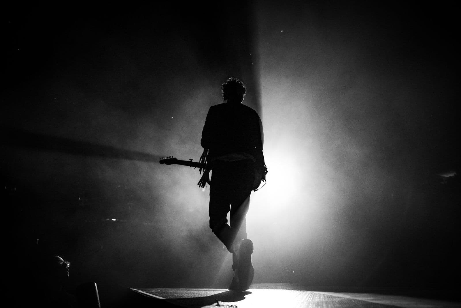 A performer lit by a single spotlight on a dark stage