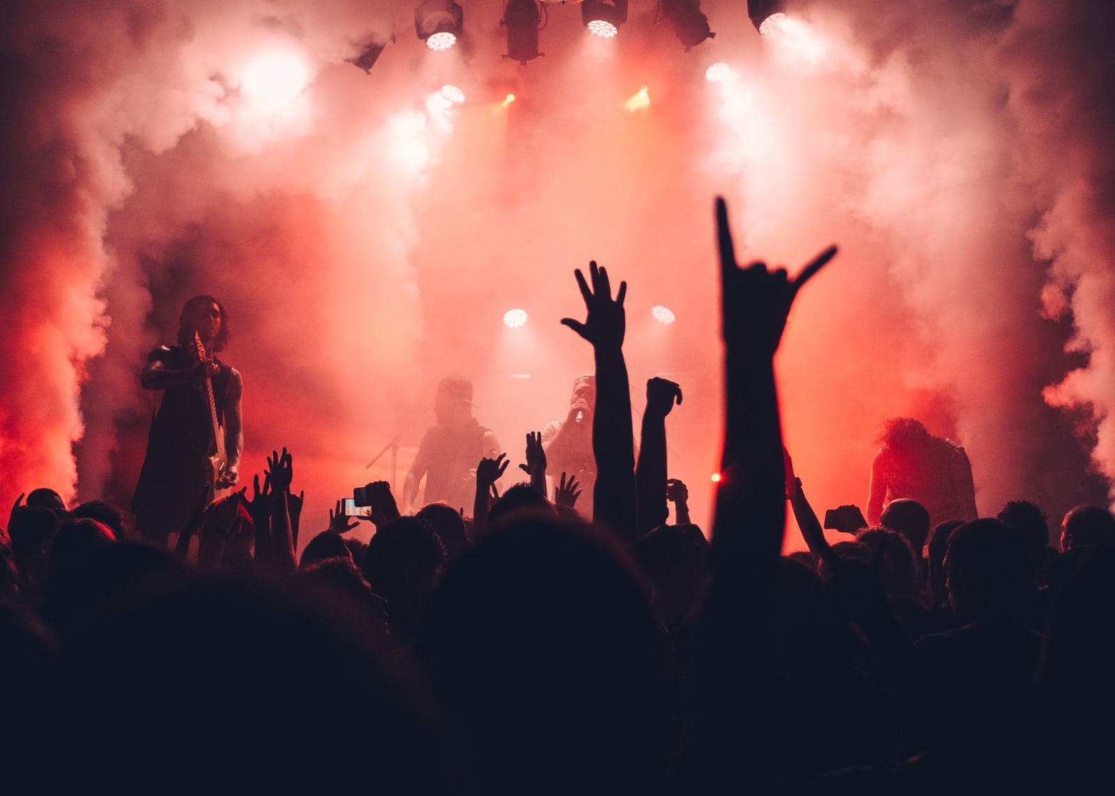 A crowd with raised hands in front of a lit stage
